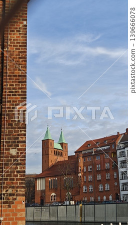 Historic red brick buildings with green spires and blue sky in urban setting, showcasing architectural details and contrasting modern structures nearby Historic red brick buildings with green spires and blue sky in urban setting, showcasing architectural details and contrasting modern structures nearby 139666078