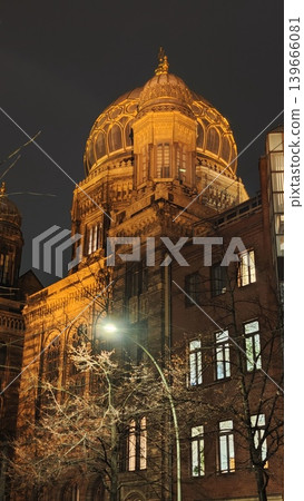 Historic synagogue features a beautifully illuminated dome at night, with intricate architectural details and trees visible in the urban environment Historic synagogue features a beautifully illuminated dome at night, with intricate architectural details and trees visible in the urban environment 139666081