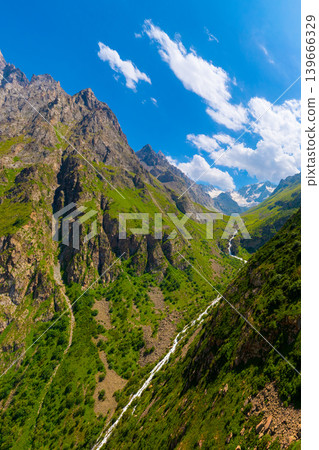 Jagged green mountain slopes with flowing river and peaks Jagged green mountain slopes with flowing river and peaks 139666329