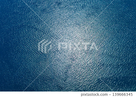 Aerial view of rippling blue water with sun reflections Aerial view of rippling blue water with sun reflections 139666345