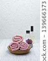 A white table with pink towels, a houseplant, shampoo, conditioner, and soap, offering space for your message or branding. 139666373