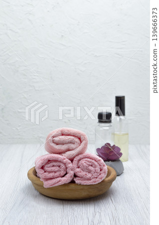 A white table with pink towels, a houseplant, shampoo, conditioner, and soap, offering space for your message or branding. A white table with pink towels, a houseplant, shampoo, conditioner, and soap, offering space for your message or branding. 139666373