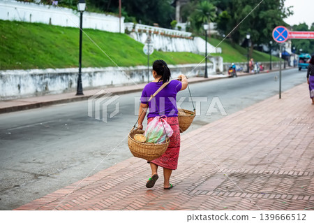 Traditional street vendor walking with baskets in Luang Prabang, Laos. 139666512
