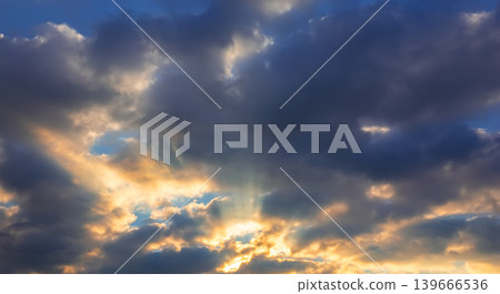 Cloudy sky with sun rays piercing through dramatic formations. Strong atmospheric scene suitable for weather concepts, backgrounds, spirituality and emotional visual storytelling. Cloudy sky with sun rays piercing through dramatic formations. Strong atmospheric scene suitable for weather concepts, backgrounds, spirituality and emotional visual storytelling. 139666536