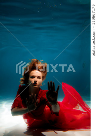Vivid underwater image featuring woman in red attire staring closely Vivid underwater image featuring woman in red attire staring closely 139667179