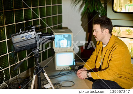 Independent filmmaker analyzing retro camera and monitor in studio Independent filmmaker analyzing retro camera and monitor in studio 139667247
