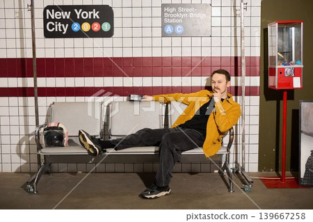 Laidback individual wearing yellow shirt enjoys downtime on city bench Laidback individual wearing yellow shirt enjoys downtime on city bench 139667258