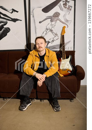 Caucasian band member taking downtime on sofa with guitar 139667272