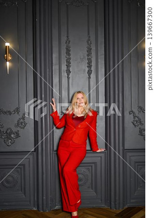 Stylish lady in red. Selfassured woman against ornate vintage wall setting Stylish lady in red. Selfassured woman against ornate vintage wall setting 139667300