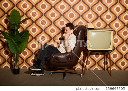 Individual sitting with retro television and patterned wall decor Individual sitting with retro television and patterned wall decor 139667305