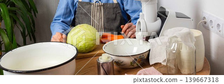 A 53-year-old man sits in his kitchen, ready to ferment cabbage and carrots. He focuses on the task ahead with equipment and fresh ingredients nearby, banner A 53-year-old man sits in his kitchen, ready to ferment cabbage and carrots. He focuses on the task ahead with equipment and fresh ingredients nearby, banner 139667318