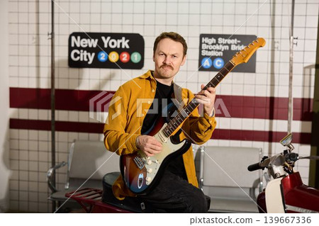 Urban performer showcasing colorful guitar near station platform Urban performer showcasing colorful guitar near station platform 139667336