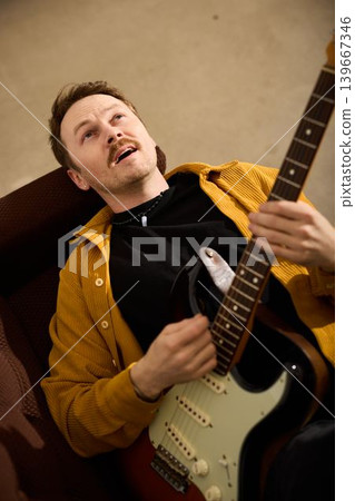 Caucasian singersongwriter rehearsing and smiling with electric guitar Caucasian singersongwriter rehearsing and smiling with electric guitar 139667346
