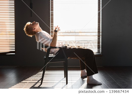 Young man relaxes in chair contemplating strategy amid sunlight Young man relaxes in chair contemplating strategy amid sunlight 139667434