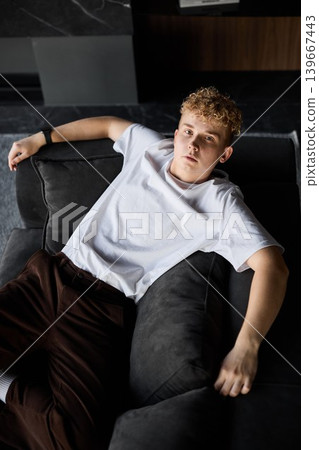 Fashionably dressed young man relaxing on sofa in urban studio apartment 139667443