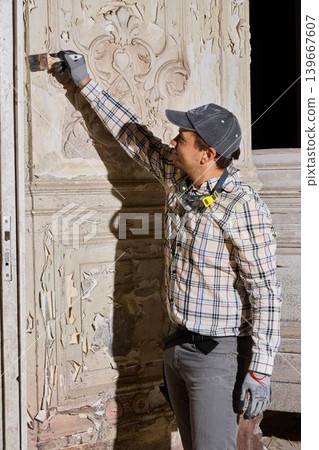 Renovation technician carefully prepares surface for restoration work 139667607