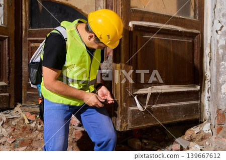 Construction worker inspecting door structure carefully Construction worker inspecting door structure carefully 139667612