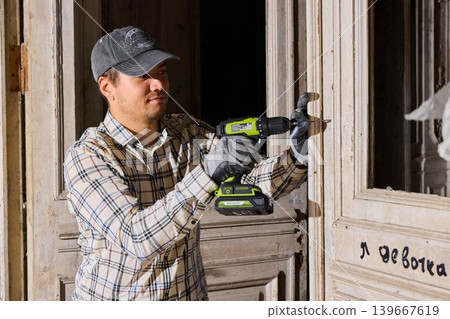 Professional examining doorframe with tools and careful attention Professional examining doorframe with tools and careful attention 139667619