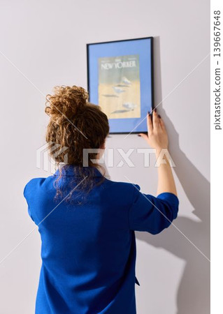 Female in casual home attire evaluates wall level for hanging picture Female in casual home attire evaluates wall level for hanging picture 139667648