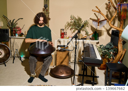 Creative artist playing handpan amid wellequipped studio Creative artist playing handpan amid wellequipped studio 139667662