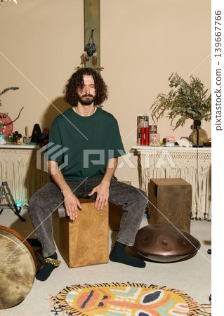 Person resting on percussion box in warm home space with greenery Person resting on percussion box in warm home space with greenery 139667766