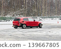 Red vehicle maneuvering through cones during winter autocross event 139667805