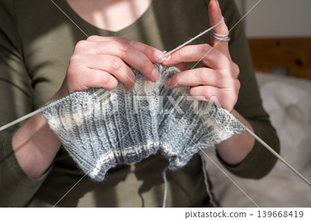 Woman knitting, close-up hands with yarn and knitted scarf. Handicraft hobby concept Woman knitting, close-up hands with yarn and knitted scarf. Handicraft hobby concept 139668419
