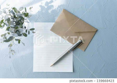 A letter image with stationery, a craft envelope, and a pen against a blue background. 139668423