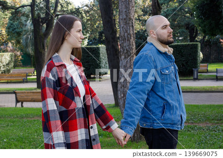 Young couple walking together outdoors in city park Young couple walking together outdoors in city park 139669075