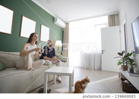 Married couple playing console game at home. Excited active pair video game Married couple playing console game at home. Excited active pair video game 139669085