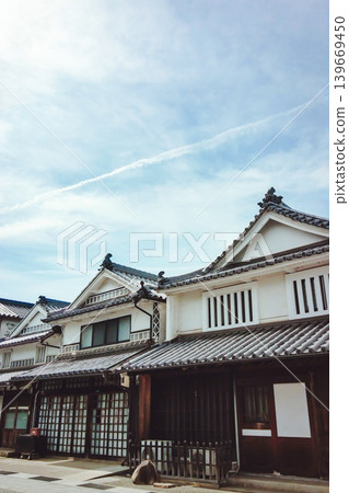 藍天中一道飛機尾跡,以及一排排傳統的日式瓦片屋頂。 藍天中一道飛機尾跡,以及一排排傳統的日式瓦片屋頂。 139669450