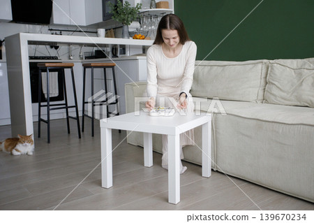Pretty woman opening jewelry box and sitting on sofa in modern interior at home Pretty woman opening jewelry box and sitting on sofa in modern interior at home 139670234