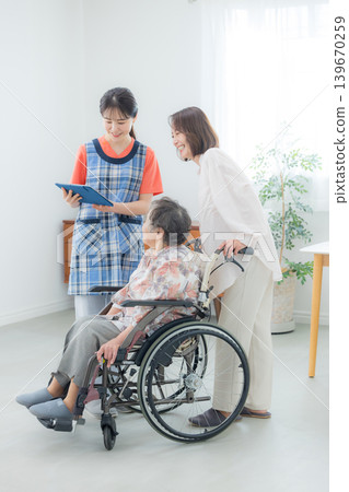 A caregiver using a tablet and an elderly person in a wheelchair A caregiver using a tablet and an elderly person in a wheelchair 139670259