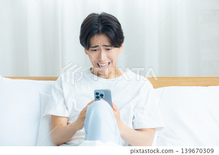 清晨,一個男人憂心忡忡地看著他的智慧型手機。 清晨,一個男人憂心忡忡地看著他的智慧型手機。 139670309