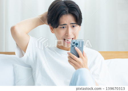 清晨,一個男人憂心忡忡地看著他的智慧型手機。 清晨,一個男人憂心忡忡地看著他的智慧型手機。 139670313
