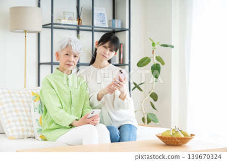 A senior mother and her middle-aged daughter struggling with smartphone use A senior mother and her middle-aged daughter struggling with smartphone use 139670324