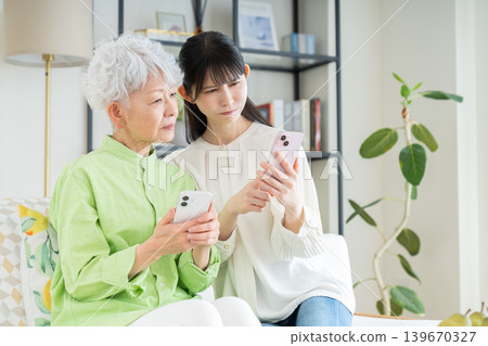 A senior mother and her middle-aged daughter struggling with smartphone use A senior mother and her middle-aged daughter struggling with smartphone use 139670327