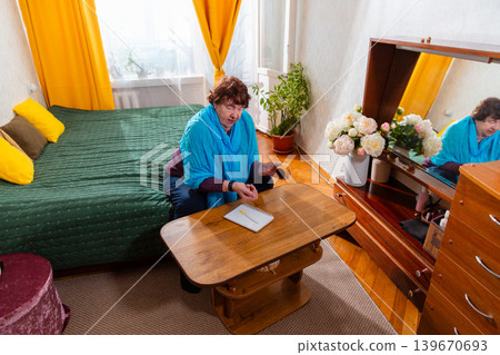 Older Caucasian woman playing dice game with attention at a table. Indoor leisure. Concept of wellbeing and hobby. Older Caucasian woman playing dice game with attention at a table. Indoor leisure. Concept of wellbeing and hobby. 139670693