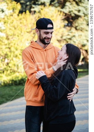 Caucasian husband and wife hugging and smiling at each other on park walkway outdoors. Marriage and romantic relationship lifestyle Caucasian husband and wife hugging and smiling at each other on park walkway outdoors. Marriage and romantic relationship lifestyle 139670767