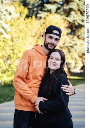 Caucasian husband and wife hugging and posing together on park walkway outdoors in daylight. Marriage and relationship lifestyle 139670769