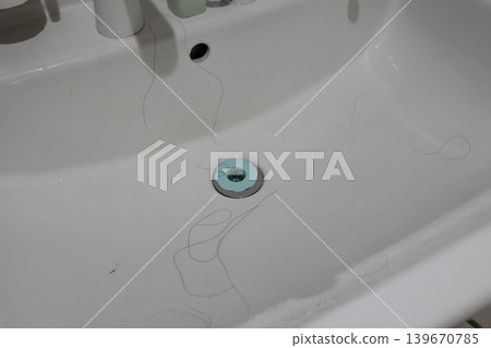 Long hairs stuck in the sink drain. Hair trap. Hair loss prevention. Long hairs stuck in the sink drain. Hair trap. Hair loss prevention. 139670785