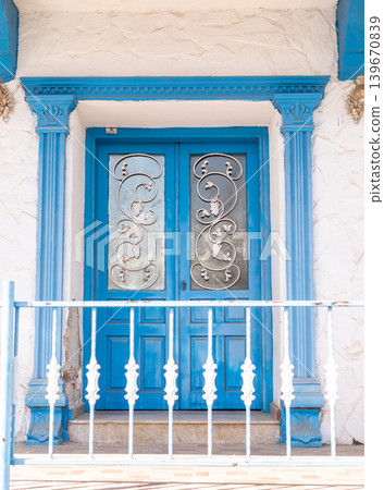 Blue double doors with decorative ironwork and white railing in front Blue double doors with decorative ironwork and white railing in front 139670839