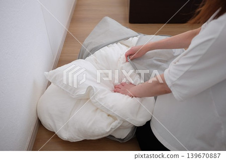 A woman puts her winter comforter into a storage bag. A woman puts her winter comforter into a storage bag. 139670887