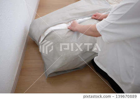 一位女士將她的冬被放進收納袋裡。 139670889
