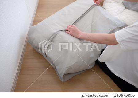 一位女士將她的冬被放進收納袋裡。 139670890