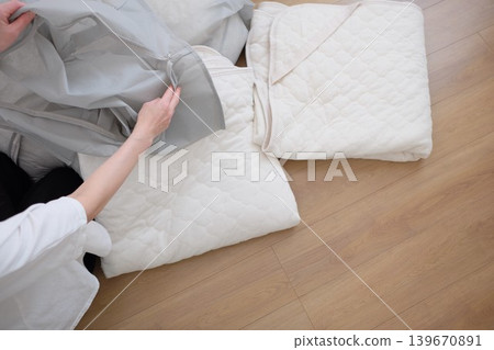 A woman puts her winter comforter into a storage bag. 139670891