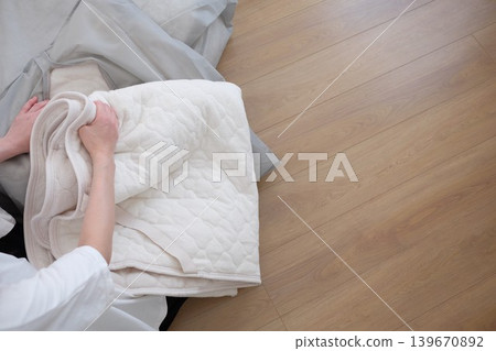 一位女士將她的冬被放進收納袋裡。 一位女士將她的冬被放進收納袋裡。 139670892