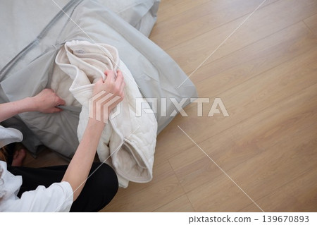 一位女士將她的冬被放進收納袋裡。 一位女士將她的冬被放進收納袋裡。 139670893