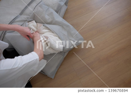 一位女士將她的冬被放進收納袋裡。 139670894