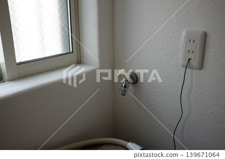 A water tap (faucet) with the washing machine hose removed. A water tap (faucet) with the washing machine hose removed. 139671064